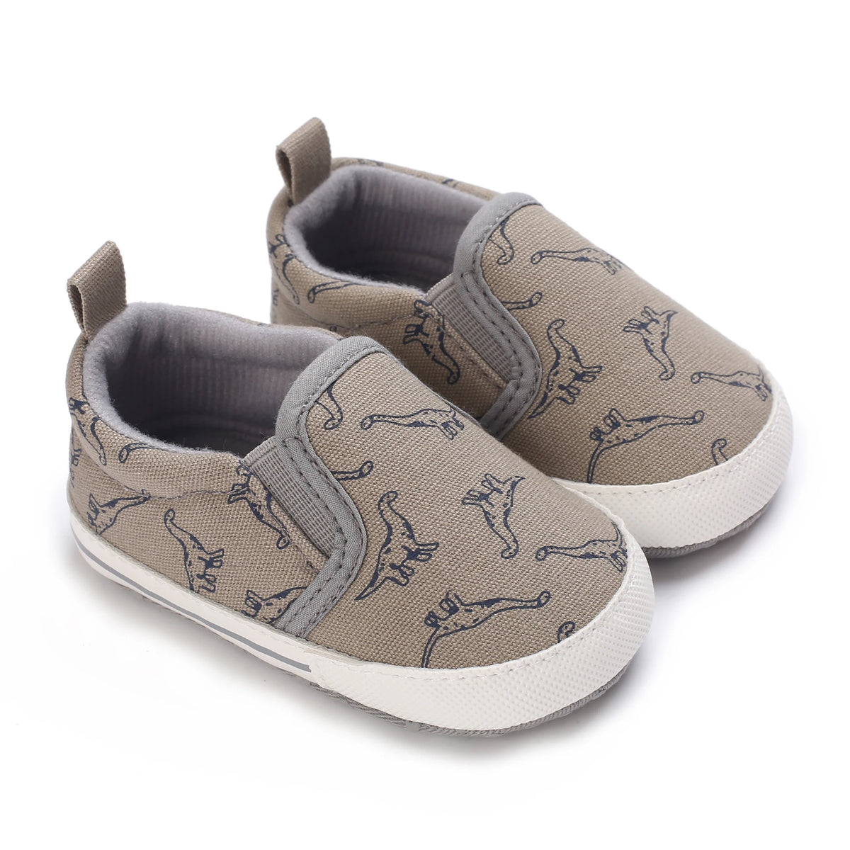 A pair of beige baby first walker sneakers with a cute dinosaur print on the fabric.