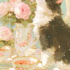 A fluffy black and white cat sits next to a pink floral arrangement and a teacup on a light green surface.