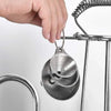 A hand is holding a stainless steel funnel with a loop attached, hanging from a wire rack.