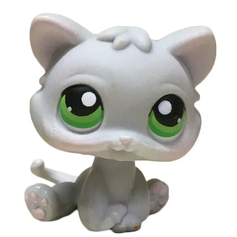 A small, white cat bobble head figurine with large green eyes.