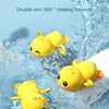 A yellow wind-up swimming duck toy floating in clear water.