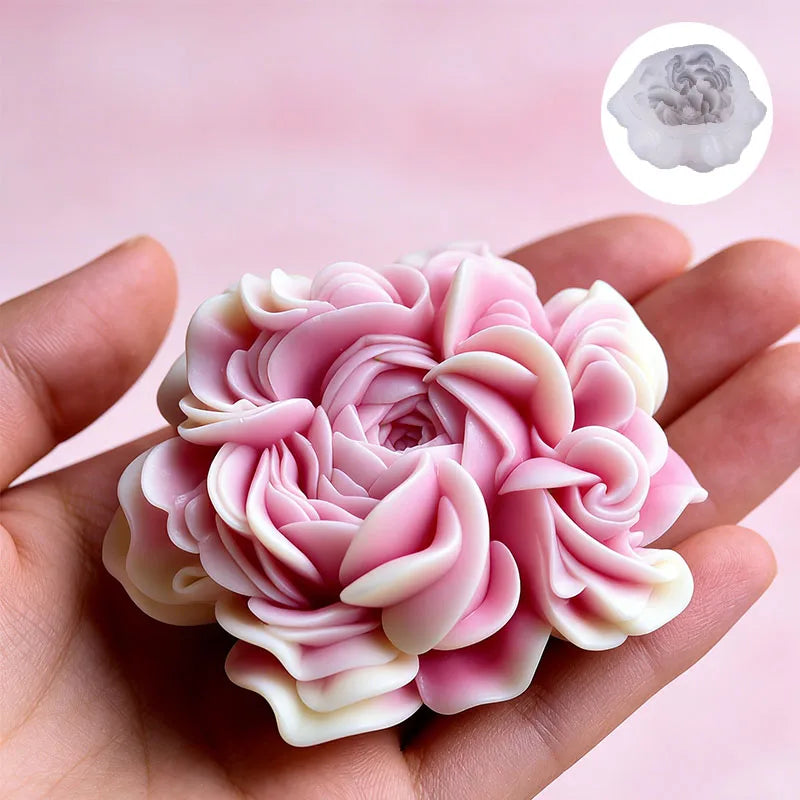 A hand holds a pink and white floral silicone candle mold with layered petals.