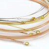 A collection of thin, coiled acoustic guitar strings in bronze and gold-colored coatings.