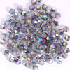 A pile of small, faceted crystal bicone glass beads for jewelry making in various shades of clear and iridescent blue.
