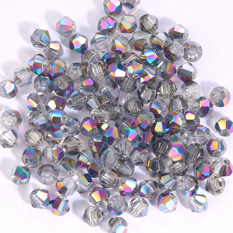 A pile of small, faceted crystal bicone glass beads for jewelry making in various shades of clear and iridescent blue.