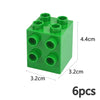 Un bloc de construction en plastique vert avec six trous ronds sur la surface supérieure, vue de dessus.