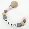 A necklace made of wooden and silicone beads with a clip, featuring the name BABY.