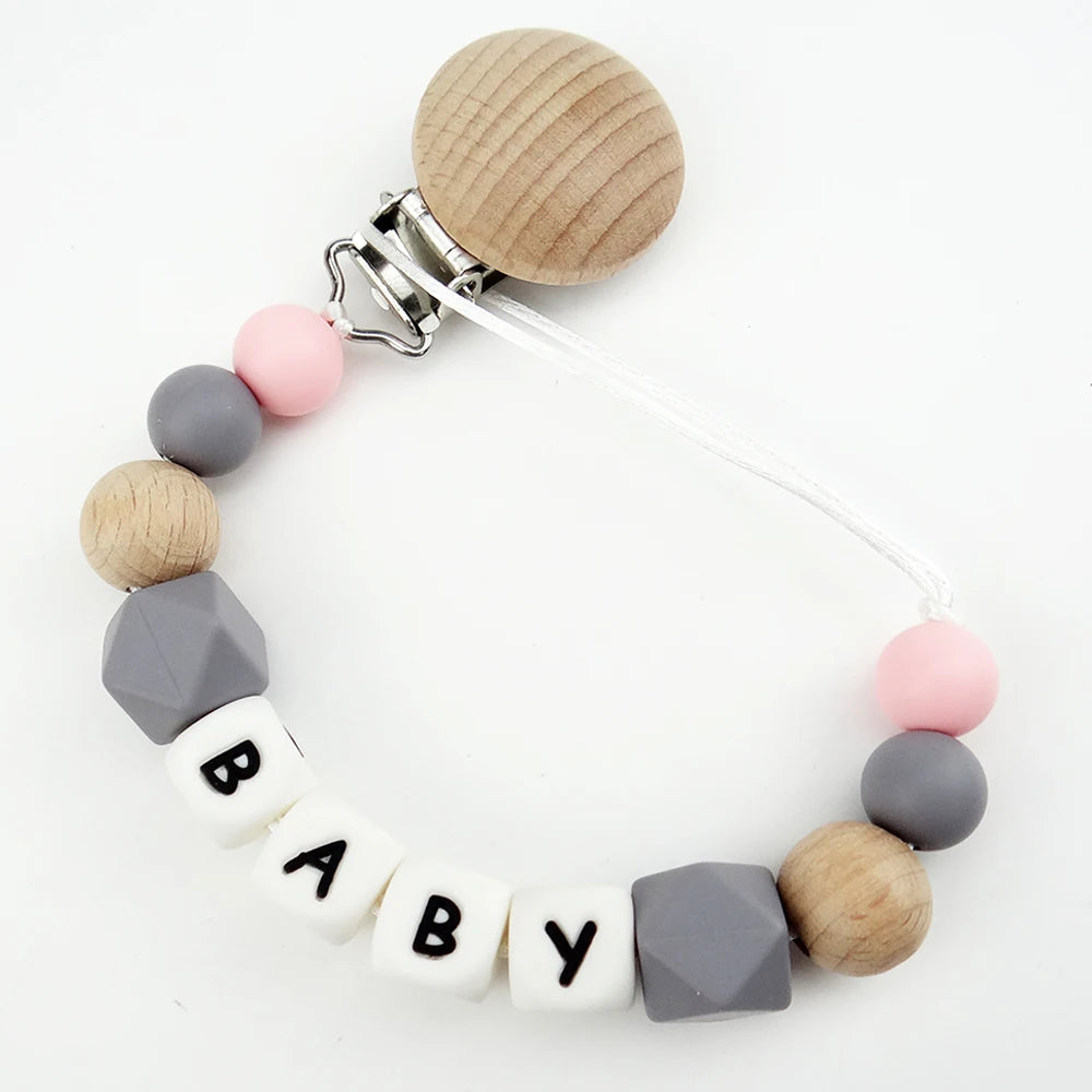 A necklace made of wooden and silicone beads with a clip, featuring the name BABY.