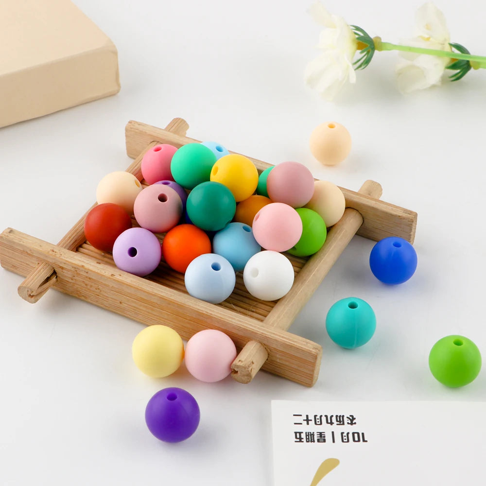 A wooden tray holds various colorful silicone round beads for jewelry making and DIY crafts.