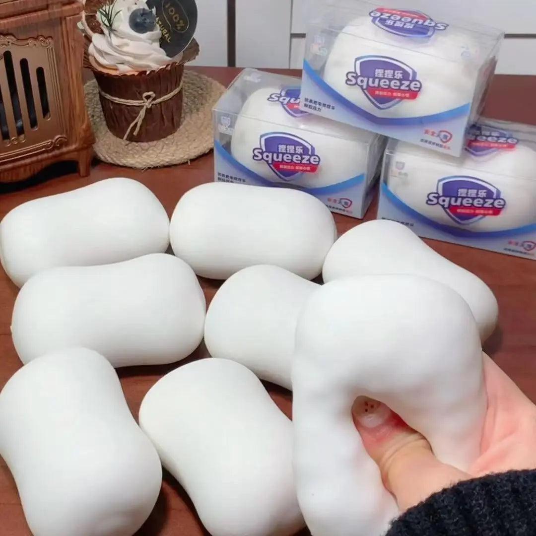 White squishy stress balls are displayed next to packaged squishies and a wooden item.
