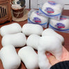 White squishy stress balls are displayed next to packaged squishies and a wooden item.