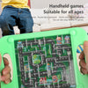 A green handheld maze game board with a maze layout and colorful buildings is held by a person.