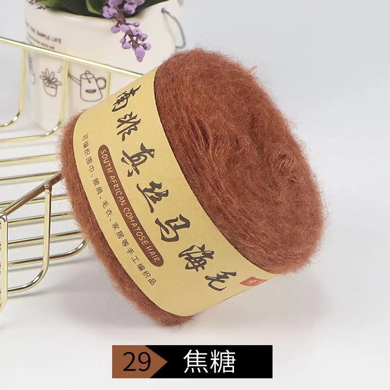 A ball of reddish-brown mohair blended yarn with a tan label is displayed next to a gold wire rack.