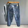 A pair of dark blue vintage loose fit denim harem jeans hanging on a wooden hanger.