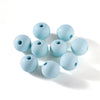 A collection of light blue matte acrylic round beads scattered on a white surface.