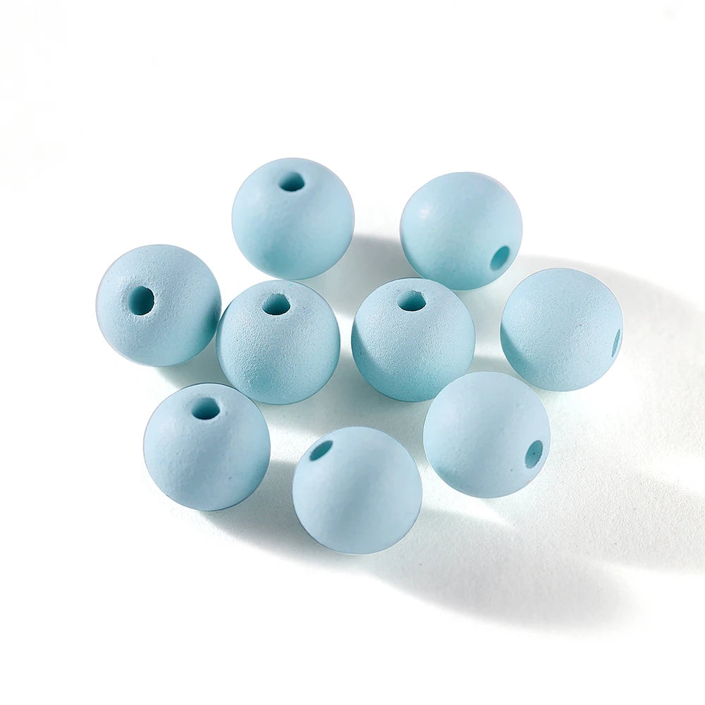 A collection of light blue matte acrylic round beads scattered on a white surface.