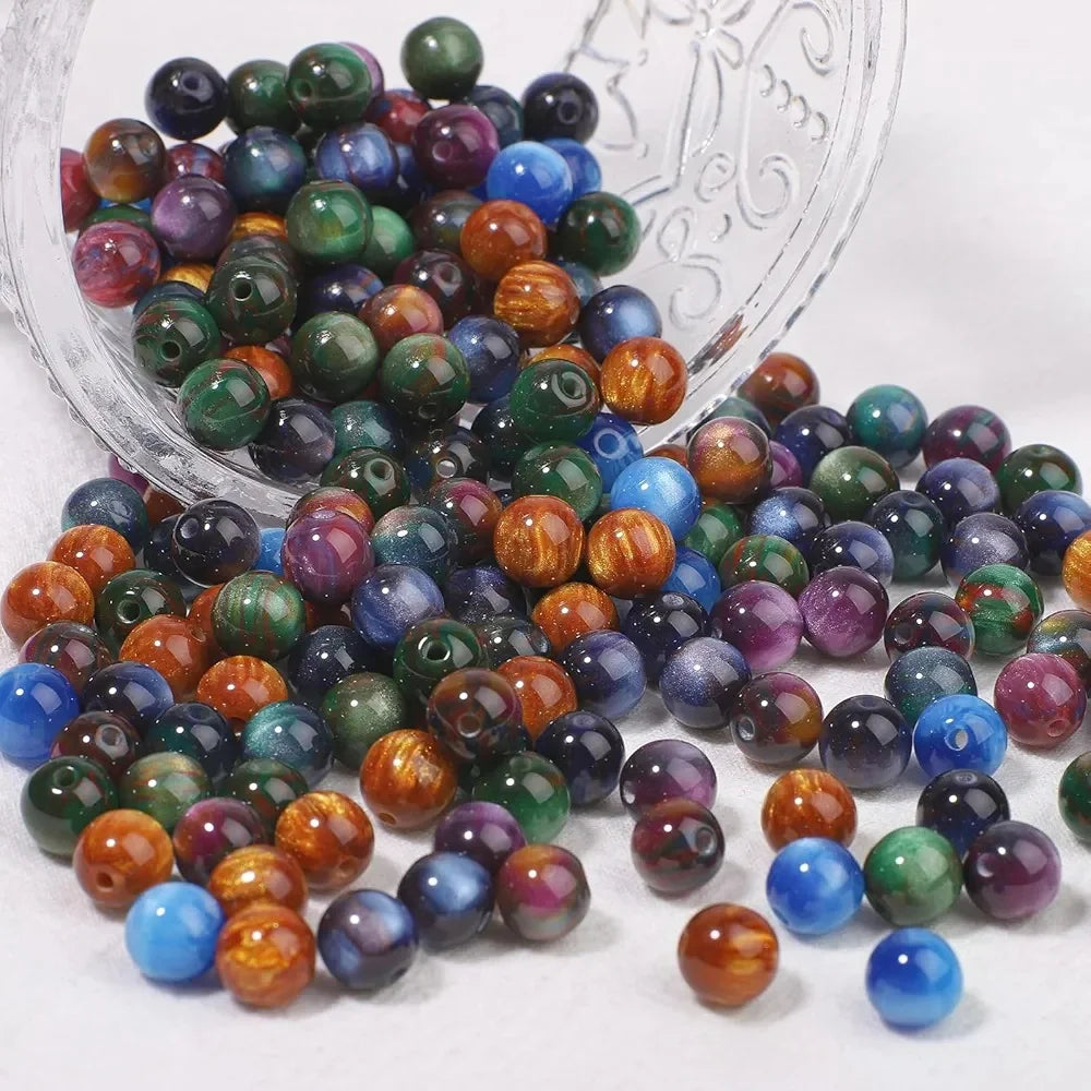 A pile of vibrant tiger eye resin beads in various shades of green, blue, purple, and orange.
