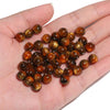 A handful of glossy, round tiger eye resin beads in various shades of brown and amber resting on a hand.