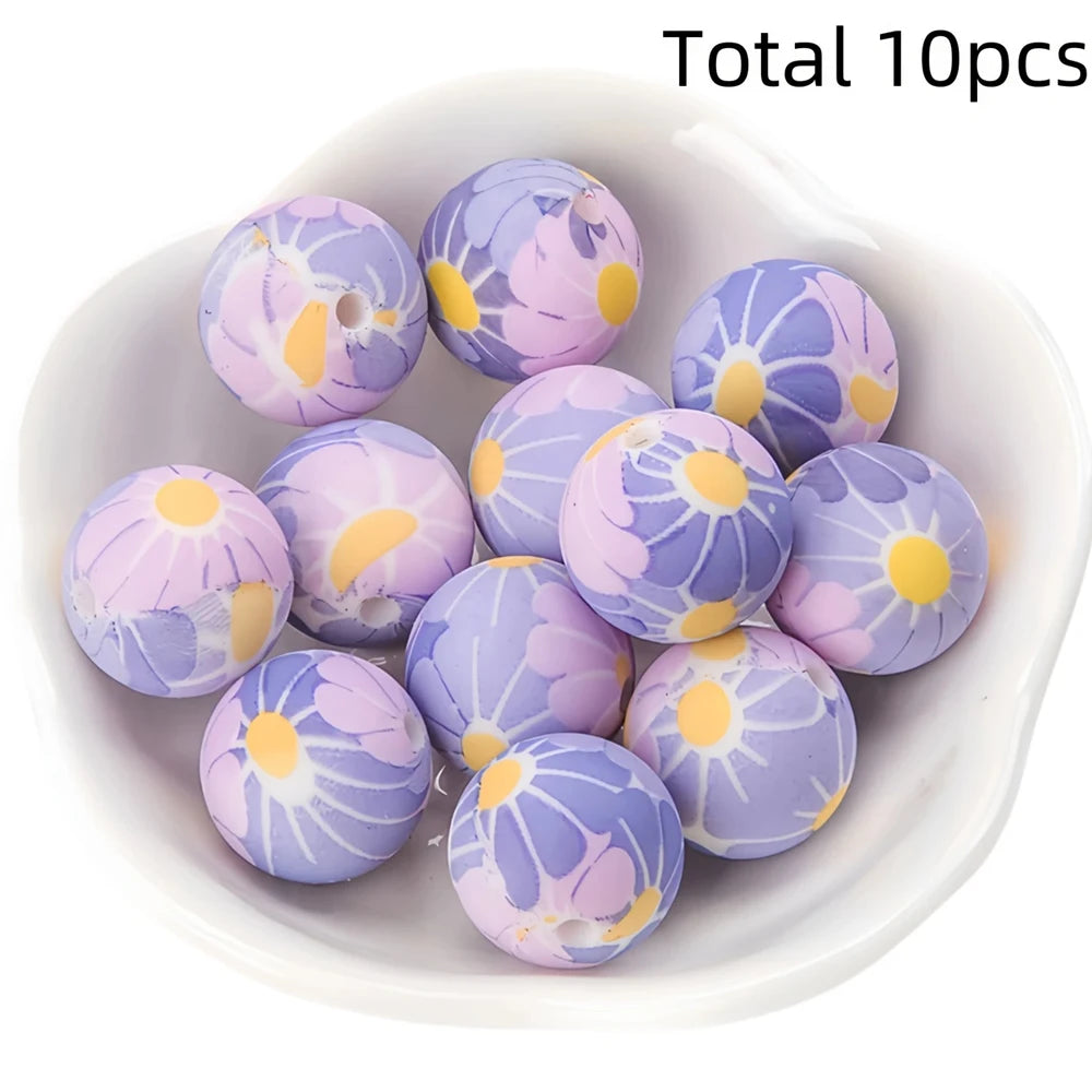 A collection of ten purple and pink printed silicone beads for DIY jewelry making displayed in a white dish.