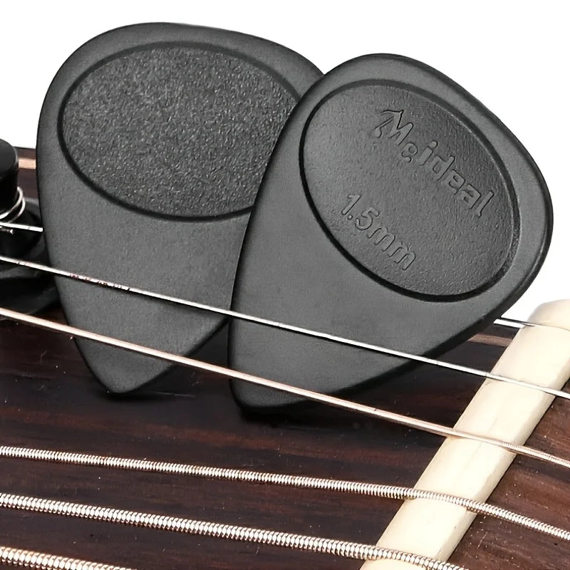 A pair of black guitar picks with anti-slip grips and a 1.5mm thickness resting on a wooden guitar fretboard.
