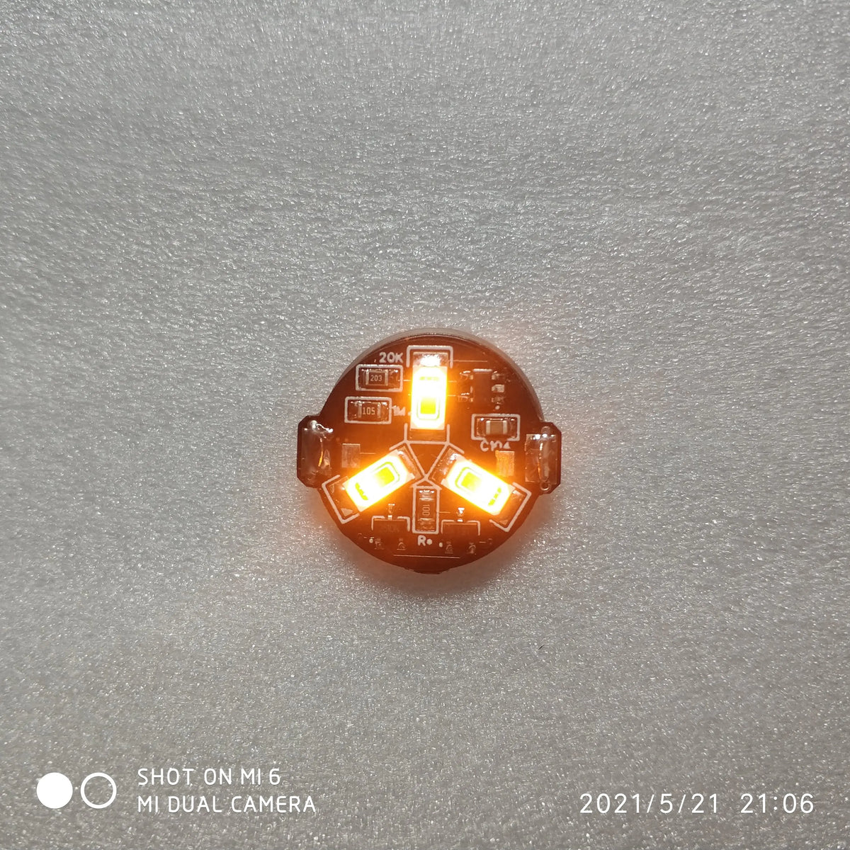 A close-up view of a magnetic LED diorama light with remote control, showing three illuminated orange lights.