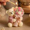 A cute pink bear figure with flowers is shown, being lit by a flame for candle making.