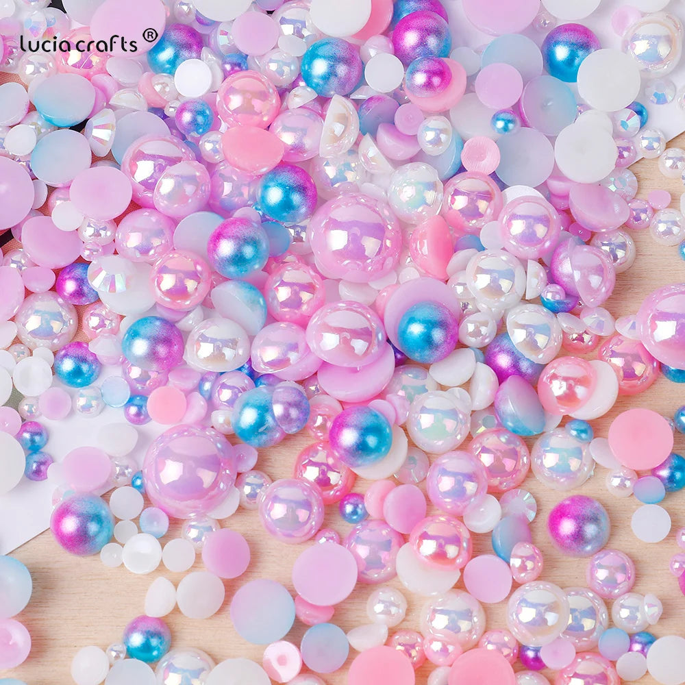 A close-up of mixed resin rhinestone pearls in various shades of pink, blue, and iridescent colors scattered on a surface.