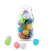 A glass jar filled with colorful rhinestone resin ball beads of various sizes and colors, with several loose beads scattered 