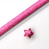 Pink glitter origami star paper strips laid diagonally on a white background for crafting