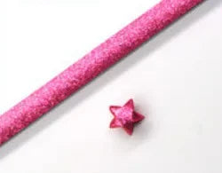 Pink glitter origami star paper strips laid diagonally on a white background for crafting