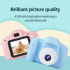 A pink and blue mini digital camera is shown with a dog in the background, illustrating brilliant picture quality.