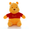 A yellow plush toy of Winnie the Pooh with orange ears and a red shirt.