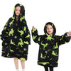A young girl wearing a black flannel hoodie sweater with green dinosaur print.