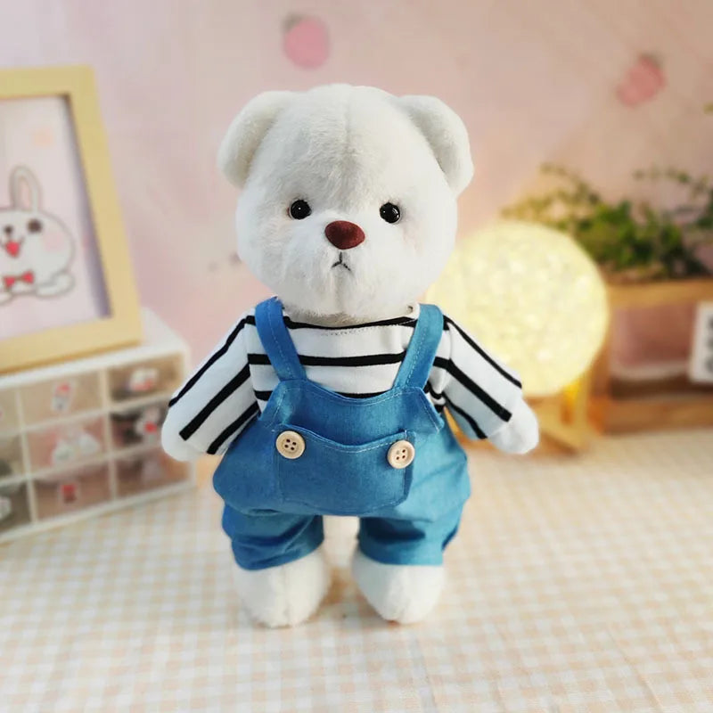 A white teddy bear plush doll wearing a blue denim overalls and striped shirt.