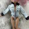A doll wearing a light blue denim jacket with black trim and dark hair, displayed against a fluffy white background.