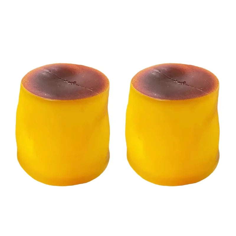 A pair of yellow caramel pudding stress balls with a dark top, showing their squishy texture.