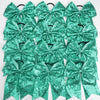 A pack of twelve teal green glitter sequin pigtail bows for girls with elastic hair ties.