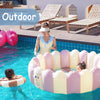 A pink inflatable round toddler pool is floating in clear water outdoors with a child inside.