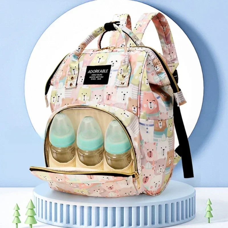 A pink cartoon print waterproof diaper bag with a backpack design and clear bottles for travel.
