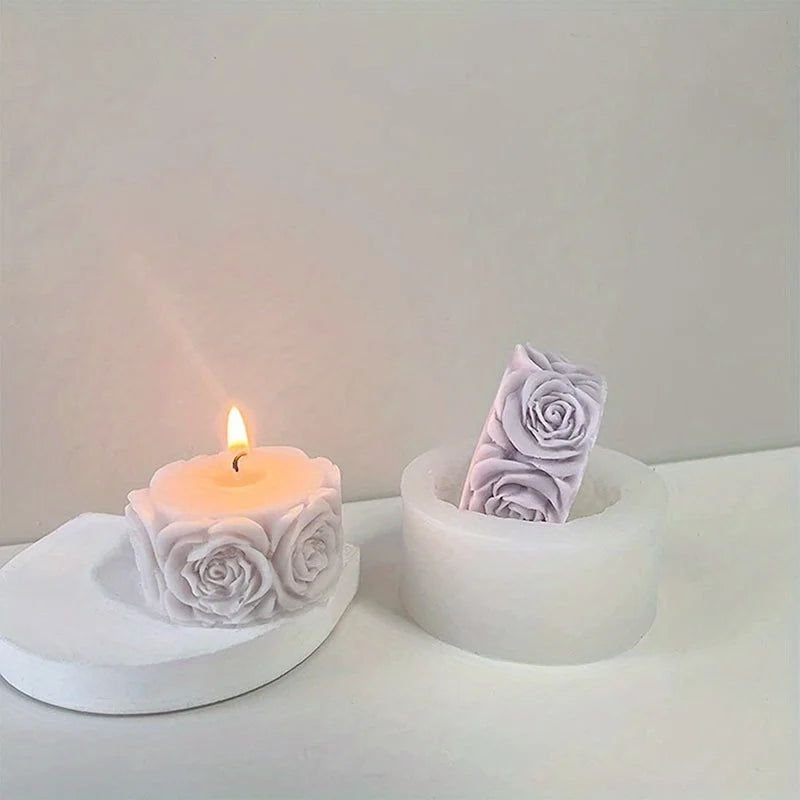 A white silicone rose candle mold with a lit candle and a molded rose flower resting on a white surface.