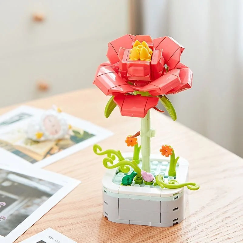 A pink rose flower building block bouquet set with yellow petals and green stem on a wooden table.