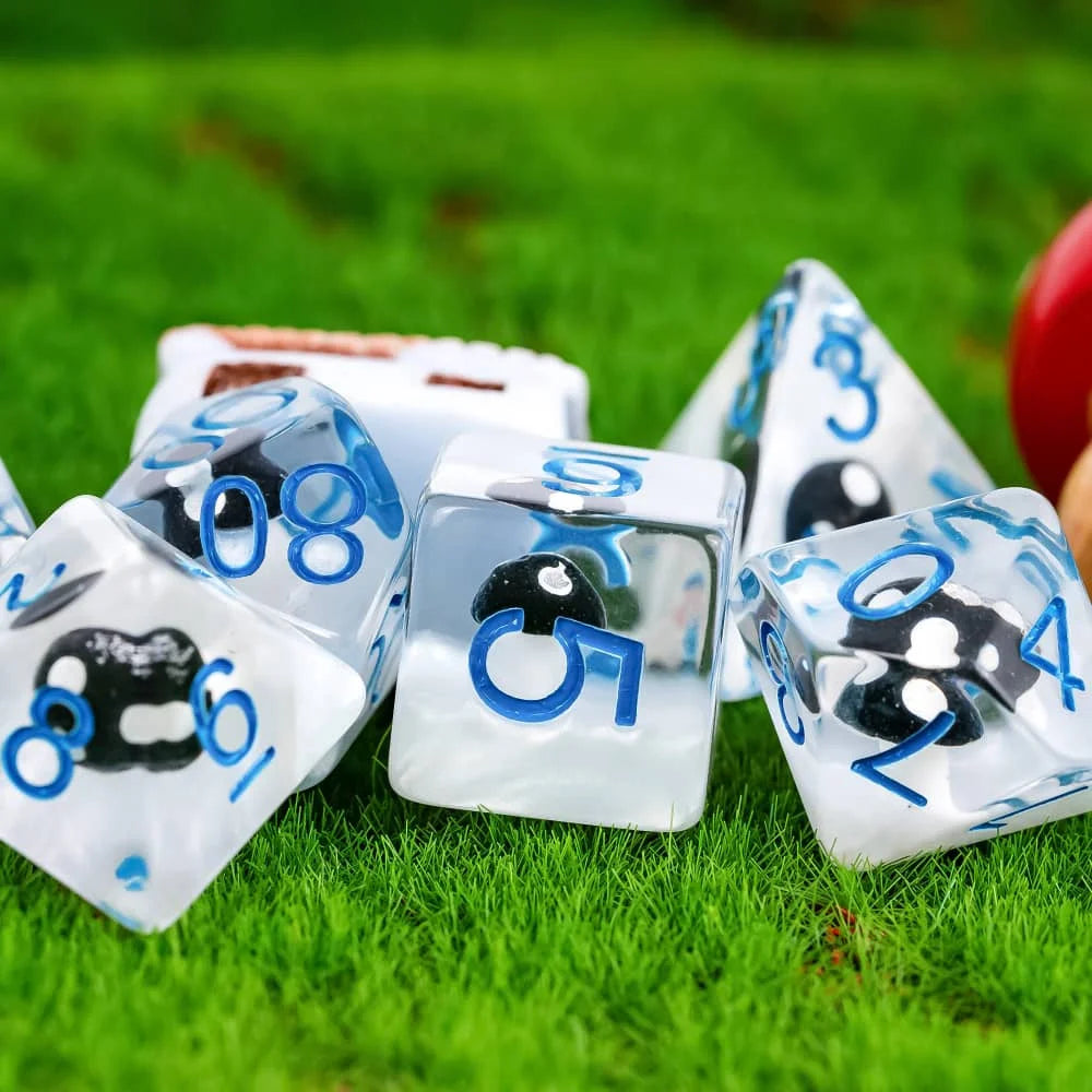 A set of white polyhedral dice featuring black mushroom designs resting on green grass.