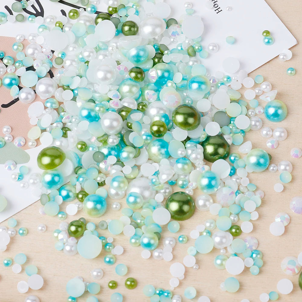 A scatter of mixed resin rhinestone pearls in shades of white, blue, and green on a light wooden surface.