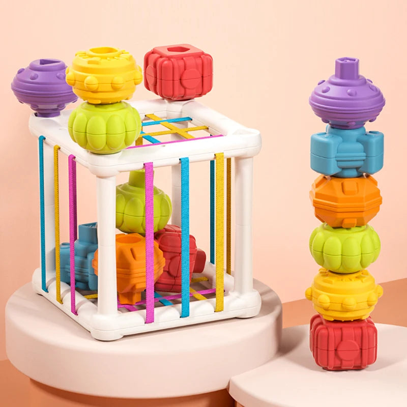 A set of colorful Montessori shape sorting cubes with elastic bands arranged in a tower and a sorting rack.