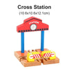 A red wooden cross station model with a clock and blue support posts, placed on a wooden track base.