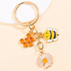 Gold-toned keychain featuring an enamel bee and a daisy flower design.