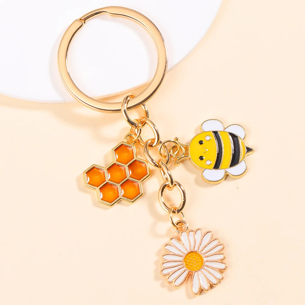 Gold-toned keychain featuring an enamel bee and a daisy flower design.