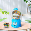 A blue candy machine dispenser filled with colorful gumballs sits on a wooden table.