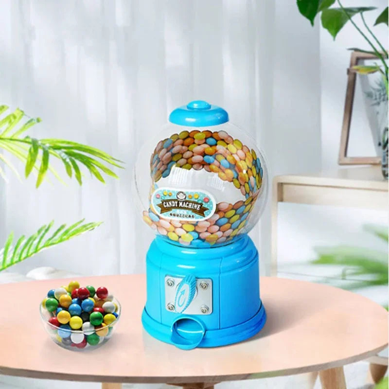 A blue candy machine dispenser filled with colorful gumballs sits on a wooden table.