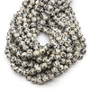 A pile of small, round, speckled natural stone beads for jewelry making in various colors.